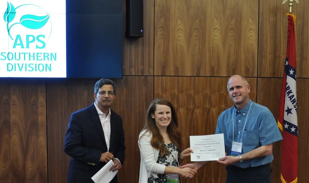 Woman receiving certificate between two men