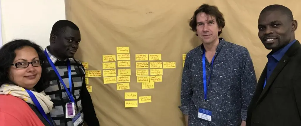 Four people around board with heart-shaped sticky notes